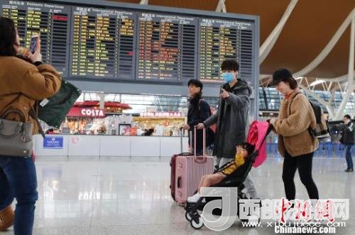 旅客帶著孩子前往辦票柜臺辦理登機手續(xù)?！∫罅⑶?攝