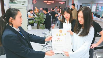河北省承德市網(wǎng)絡(luò)代購(gòu)經(jīng)營(yíng)者陳晨(右)從工作人員手中接過(guò)帶有統(tǒng)一社會(huì)信用代碼的營(yíng)業(yè)執(zhí)照。 劉環(huán)宇攝(人民圖片)