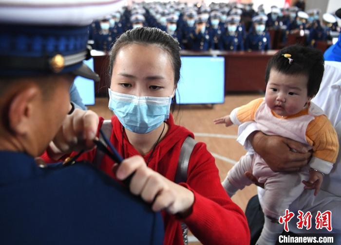 新消防員楊振的妻子彭莉與女兒現(xiàn)場(chǎng)見(jiàn)證丈夫加入“火焰藍(lán)”的神圣時(shí)刻。　劉忠俊 攝
